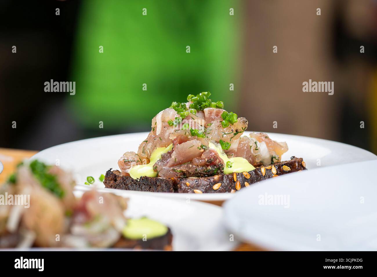 Tartre de poisson (ide) sur pain noir grillé. Tartare de poisson cru servi avec du pain de seigle sur l'assiette. Tartre de poisson gourmand. Banque D'Images