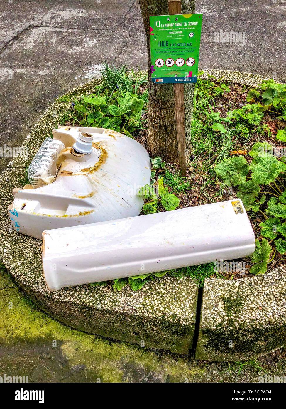 Lavabo cassé et piédestal déversés illégalement sur un minuscule terrain de jardin public à la base de l'arbre - Saint-Gilles, Bruxelles, Belgique. Banque D'Images