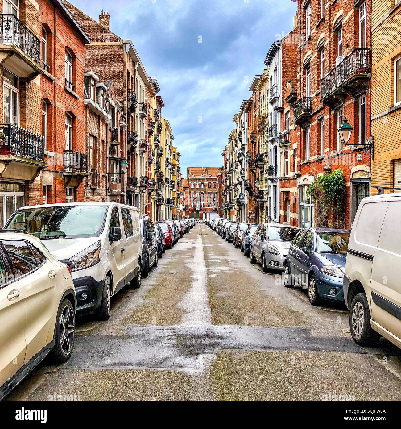 Voitures privées garées pare-chocs à pare-chocs dans une rue résidentielle de banlieue de ville - Saint-Gilles, Bruxelles, Belgique. Banque D'Images