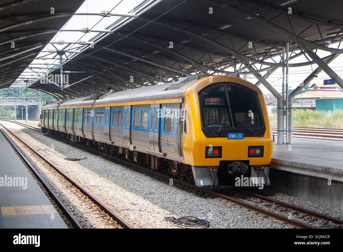 Un train de banlieue moderne KTM avec des accents jaunes et bleus attendant à une plate-forme couverte dans une gare ferroviaire malaisienne EMU Banque D'Images