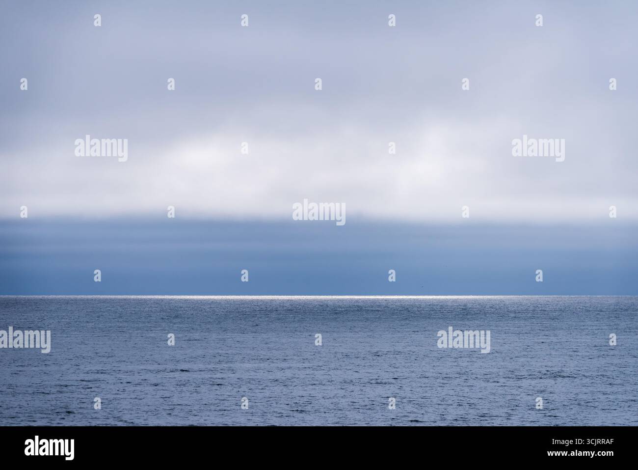 Horizon de l'océan Arctique avec réflexion du soleil Île Moffen Svalbard // OCÉAN ARCTIQUE — Un reflet du soleil scintille sur l'horizon de l'océan Arctique près de l'île Moffen dans le Svalbard, un archipel de l'océan Arctique. L'île Moffen est une réserve naturelle et un lieu de reproduction critique pour les morses. Le Svalbard est connu pour ses paysages polaires spectaculaires et est l'une des zones habitées les plus septentrionales de la Terre. La région se caractérise par son climat extrême et sa faune arctique unique. Banque D'Images