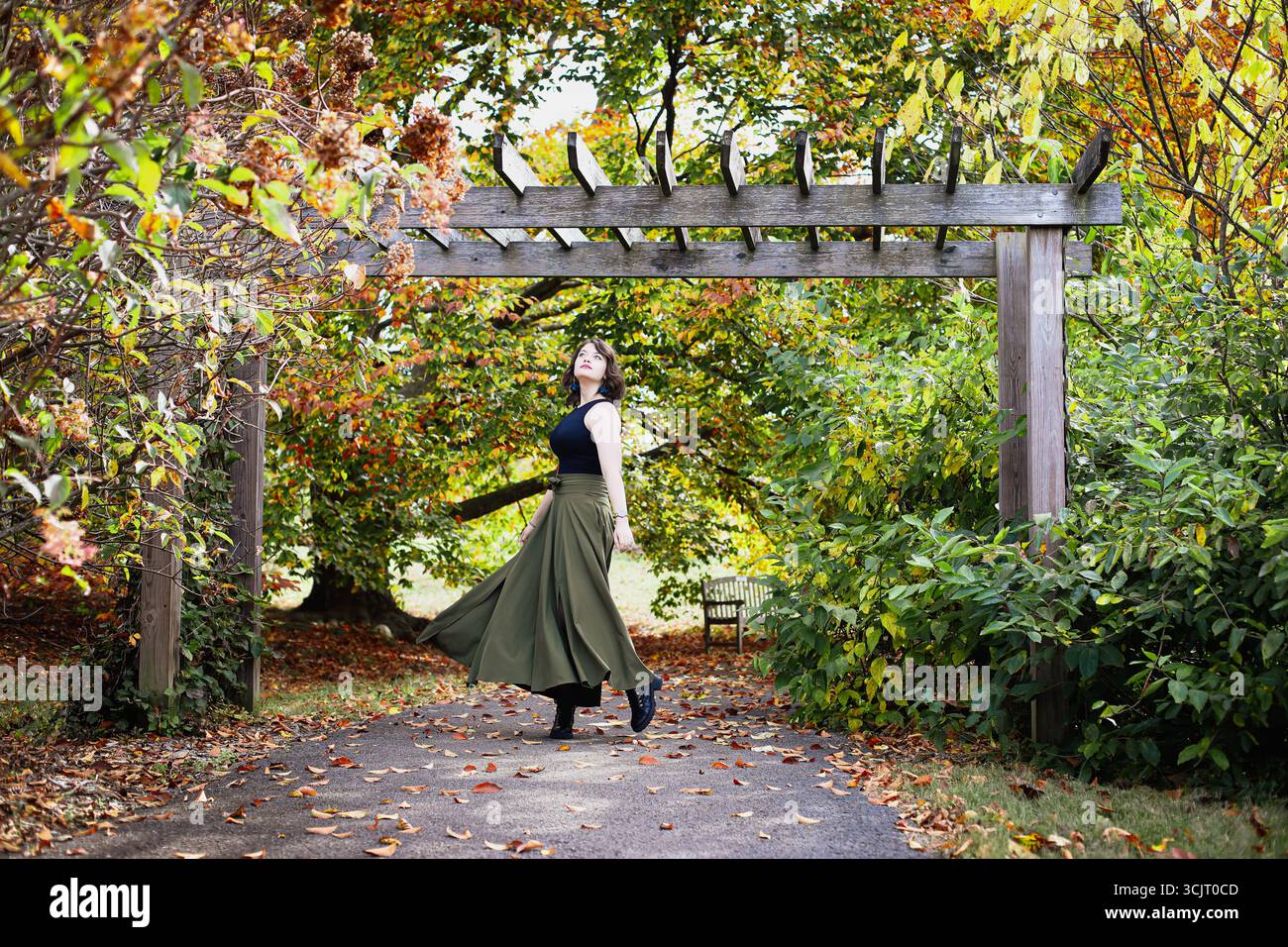 Belle jeune femme sous une tonnelle, tourbillonnant au parc avec un fond flou de belles couleurs d'automne. Banque D'Images