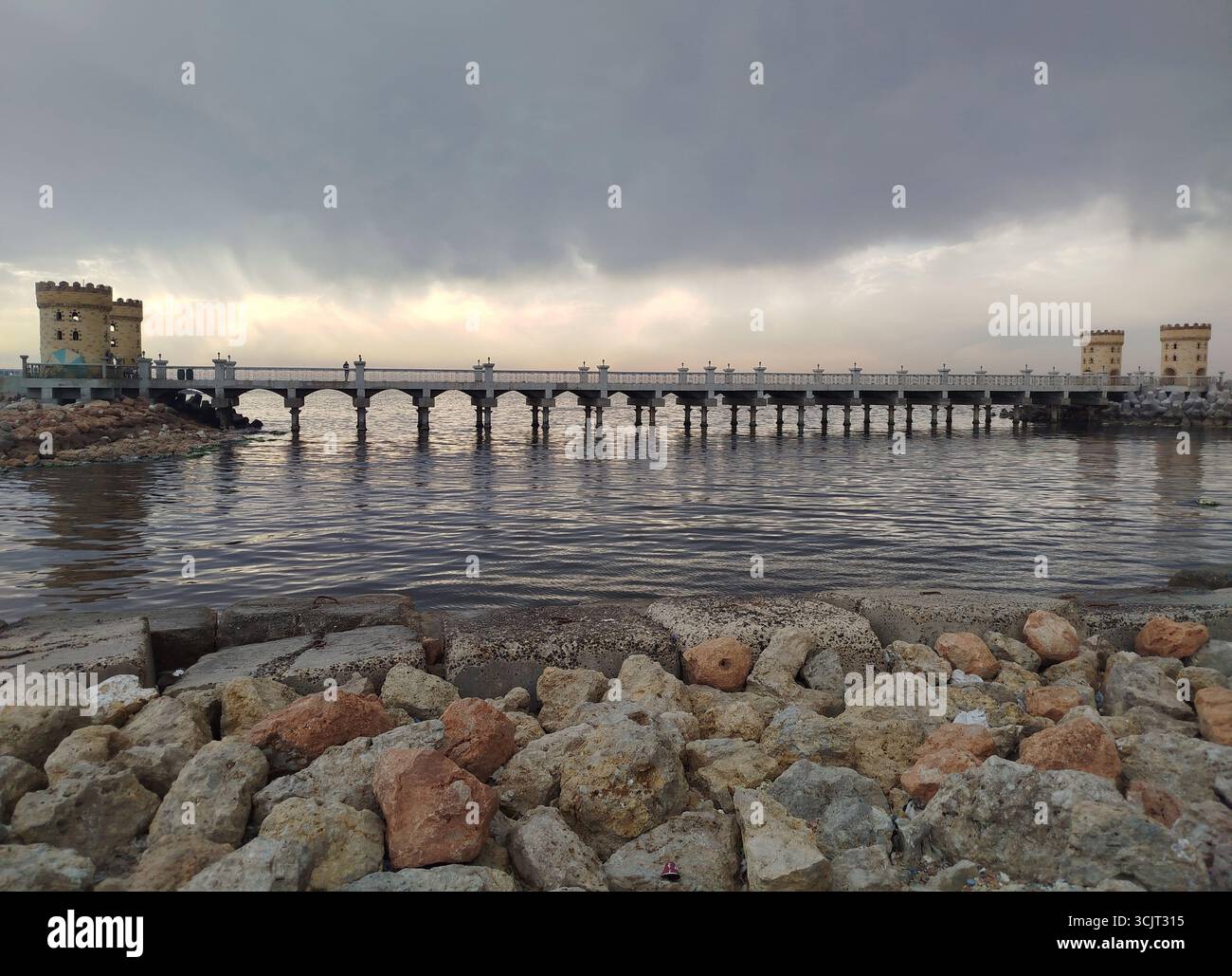 Vue panoramique sur le port d'Alexandrie avec Citadelle de Qaitbay et long pont au coucher du soleil, Egypte, reflétant l'architecture historique au bord de la mer Méditerranée Banque D'Images