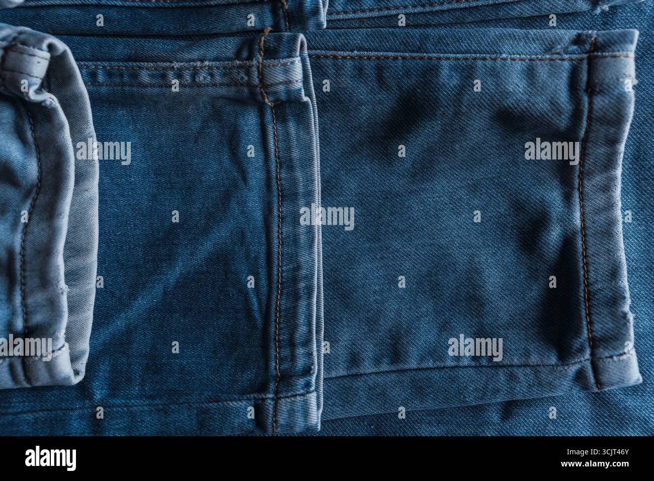 Un gros plan de jeans en denim bleu avec des textures de poche visibles et des détails de couture. Banque D'Images
