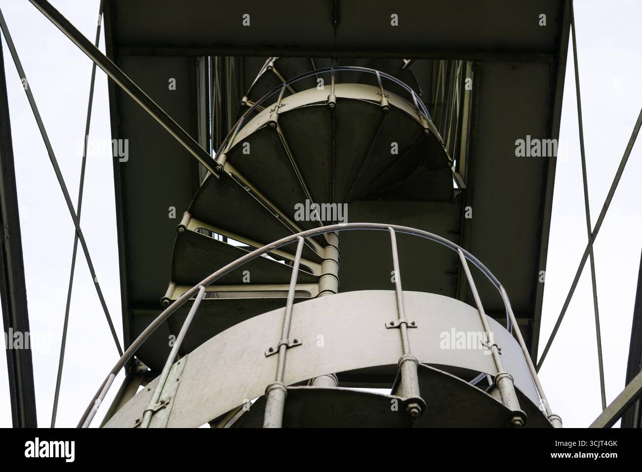 Escalier métallique en spirale vu d'en bas avec de fortes lignes géométriques. Détail de l'architecture industrielle mettant l'accent sur la structure et la symétrie. Banque D'Images