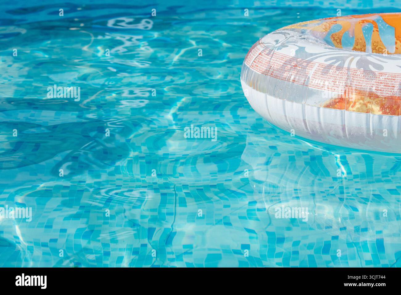 Eau de piscine lumineuse et claire avec un anneau gonflable coloré flottant sur la surface. Une scène estivale parfaite symbolisant la détente, les loisirs Banque D'Images