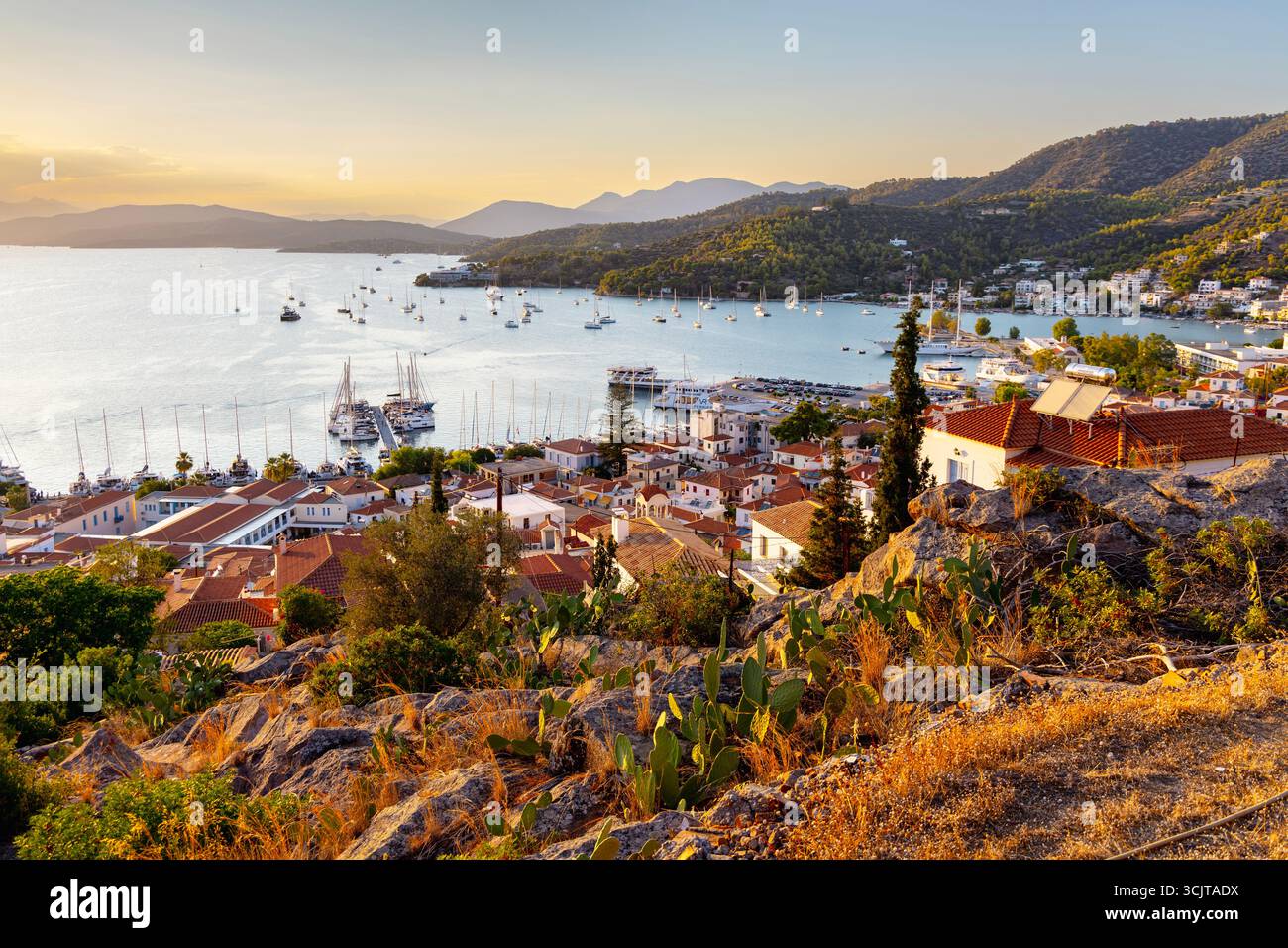 Vue de maisons, baie et port de plaisance au coucher du soleil dans la ville de Poros, île de Poros, îles Saroniques, Grèce Banque D'Images