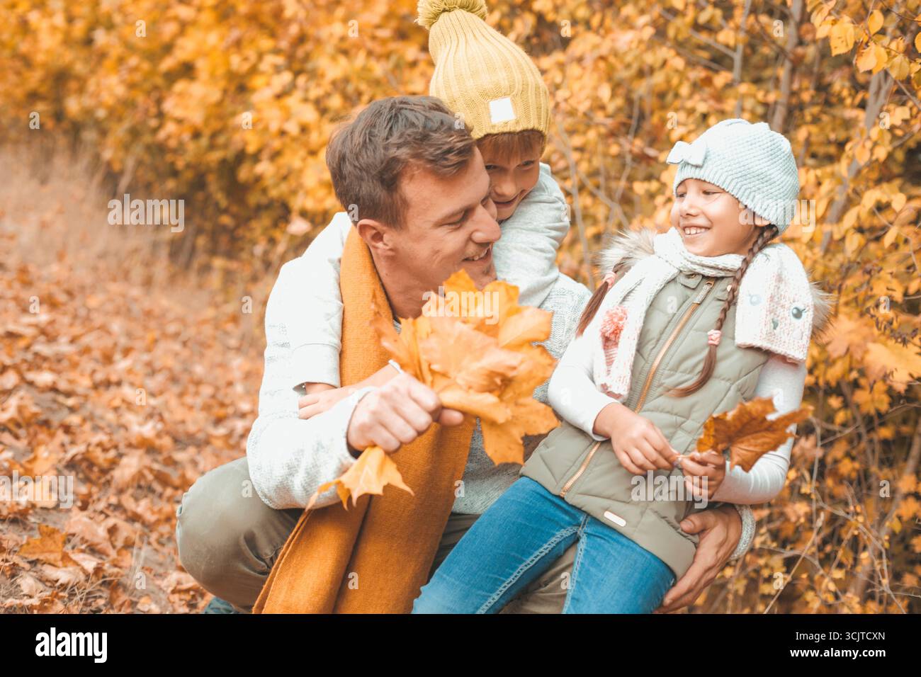 père ramassant les feuilles d'automne avec ses enfants Banque D'Images