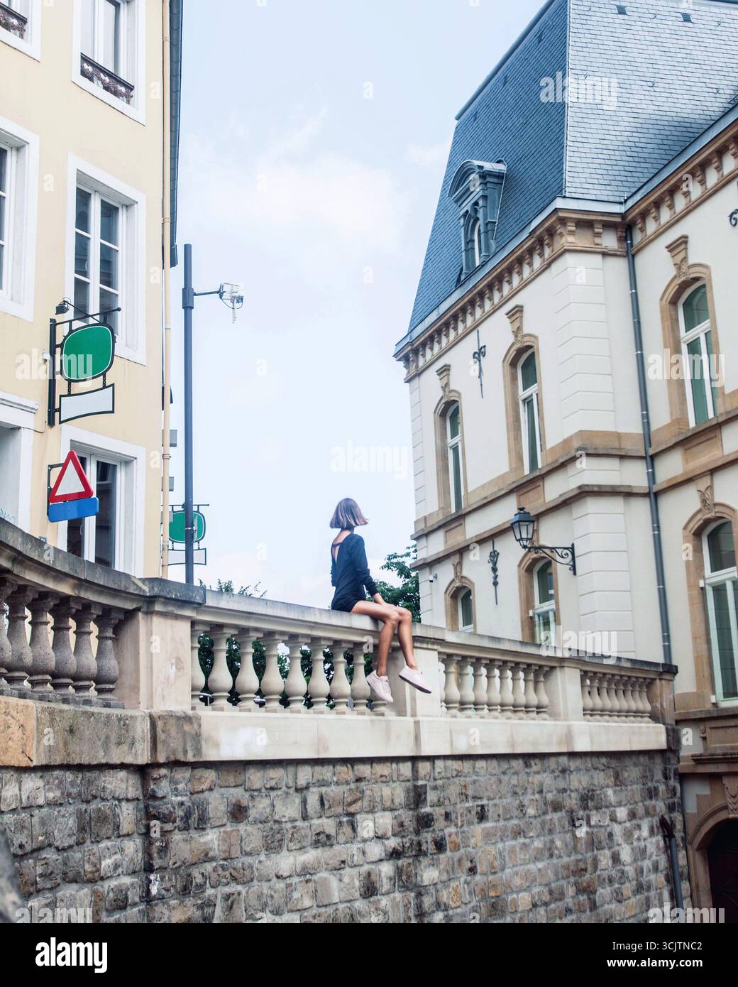 Mannequin de mode méconnaissable est assis et profitant d'une vue spectaculaire sur la ville et de l'architecture de la vieille ville de Luxembourg, tout en voyageant. Beautifu Banque D'Images