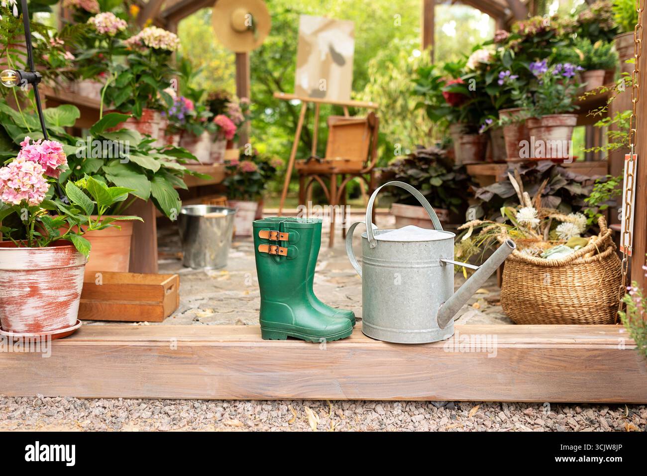 Bottes en caoutchouc vert, arrosoir. Bottes de jardin à la serre. Bottes de pluie devant la maison sur le porche. Bottes en bottes à l'arrière-cour à l'extérieur. Banque D'Images