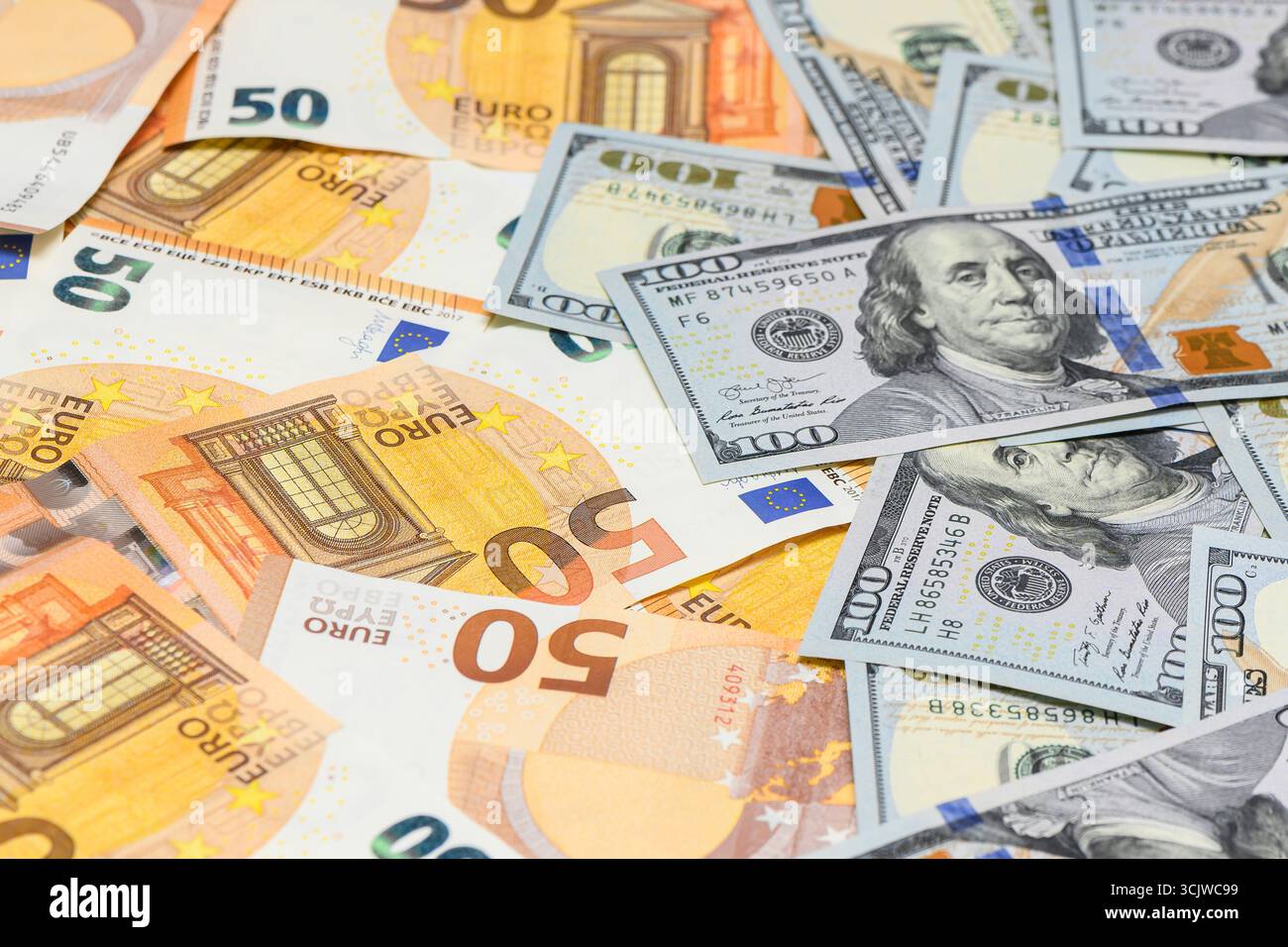 Billets de 100 dollars américains dispersés ainsi que cinquante billets en euros créant un fond de texture financière symbolisant la monnaie mondiale et le trad Banque D'Images