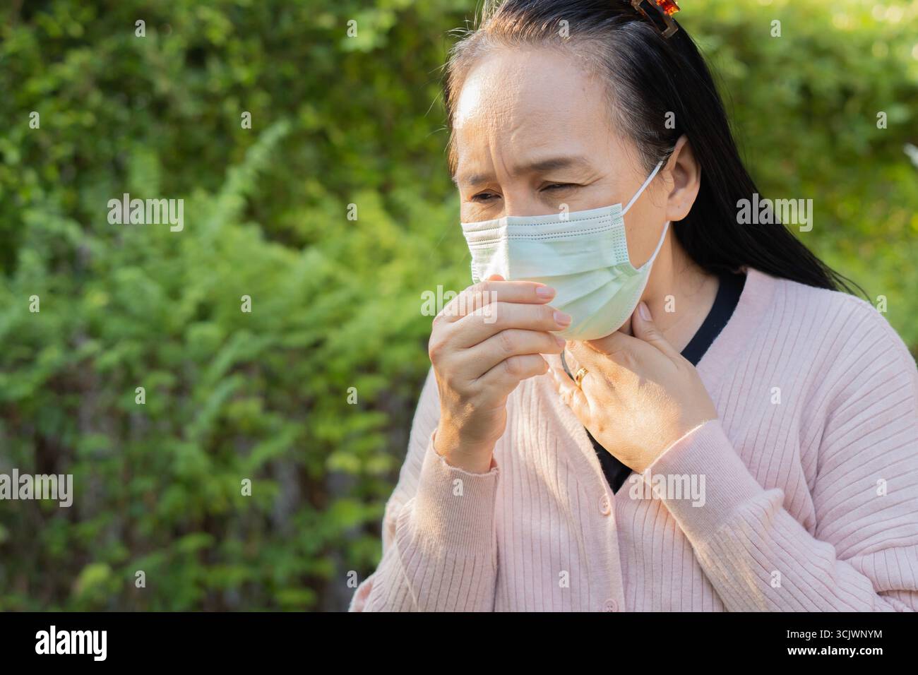 Femme se sentant malade, toussez et éternuez avec le port d'un masque de protection du visage à l'extérieur. Copier l'espace. Concept sain. Banque D'Images