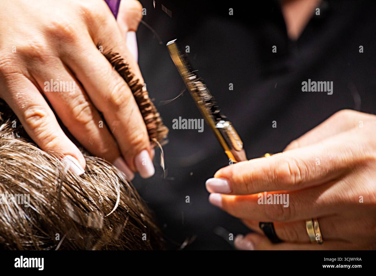 coiffeur coupe soigneusement les cheveux en sections avec des ciseaux, créant une forme Banque D'Images