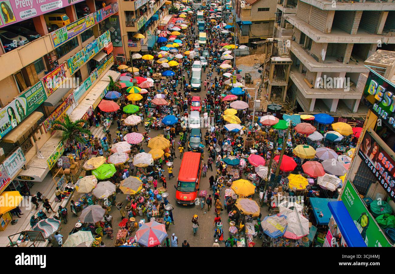Accra, Ghana - 23 mars 2024 : vue aérienne du marché de Makola palpitant avec la vie, une tapisserie vibrante de parapluies colorés ombrant les foules animées et les véhicules au milieu de l'architecture urbaine. Banque D'Images