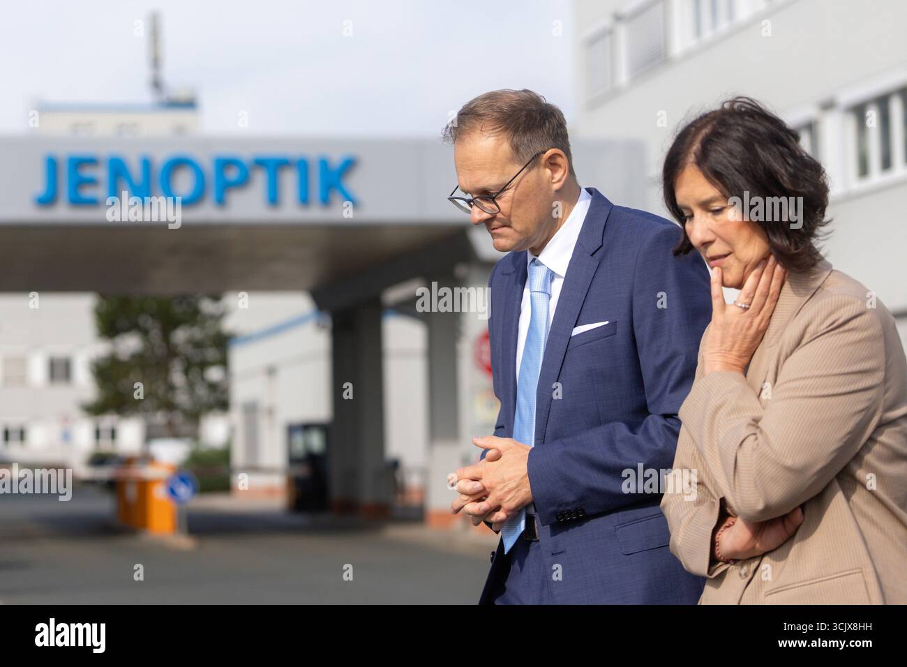 09 septembre 2025, Thuringe, Iéna/Göschwitz : Colette Boos-John (CDU), ministre de l'économie, de l'agriculture et des zones rurales et Stefan Traeger, PDG de Jenoptik, passent devant un logo de Jenoptik. Aujourd'hui, des projets d'investissement dans une installation de production de haute technologie pour l'optique semi-conductrice ont été présentés à Jenoptik. Photo : Michael Reichel/dpa Banque D'Images