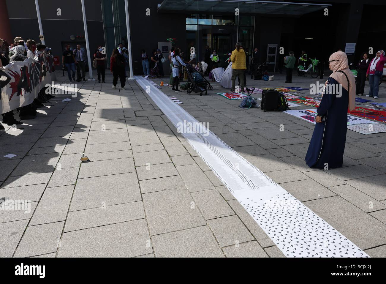 LONDRES, ROYAUME-UNI. 09th Sep, 2025. Les manifestants déroulent un énorme rouleau listant les noms des enfants tués à Gaza lors d'une manifestation devant la foire aux armes DSEI au Centre Excel. L'action, organisée par Stop the Arms Fair avec le soutien de groupes tels que Palestine Solidarity Campaign et Campaign Against the Arms Trade, a mis en évidence le coût civil du commerce mondial des armes. Crédit : Pete Speller/Alamy Live News Banque D'Images