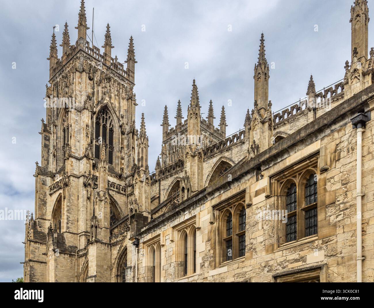 Cathédrale York Minster à York, en Angleterre, avec des flèches gothiques, des arcs pointus et des pierres ornées posées sur un ciel légèrement texturé. Banque D'Images