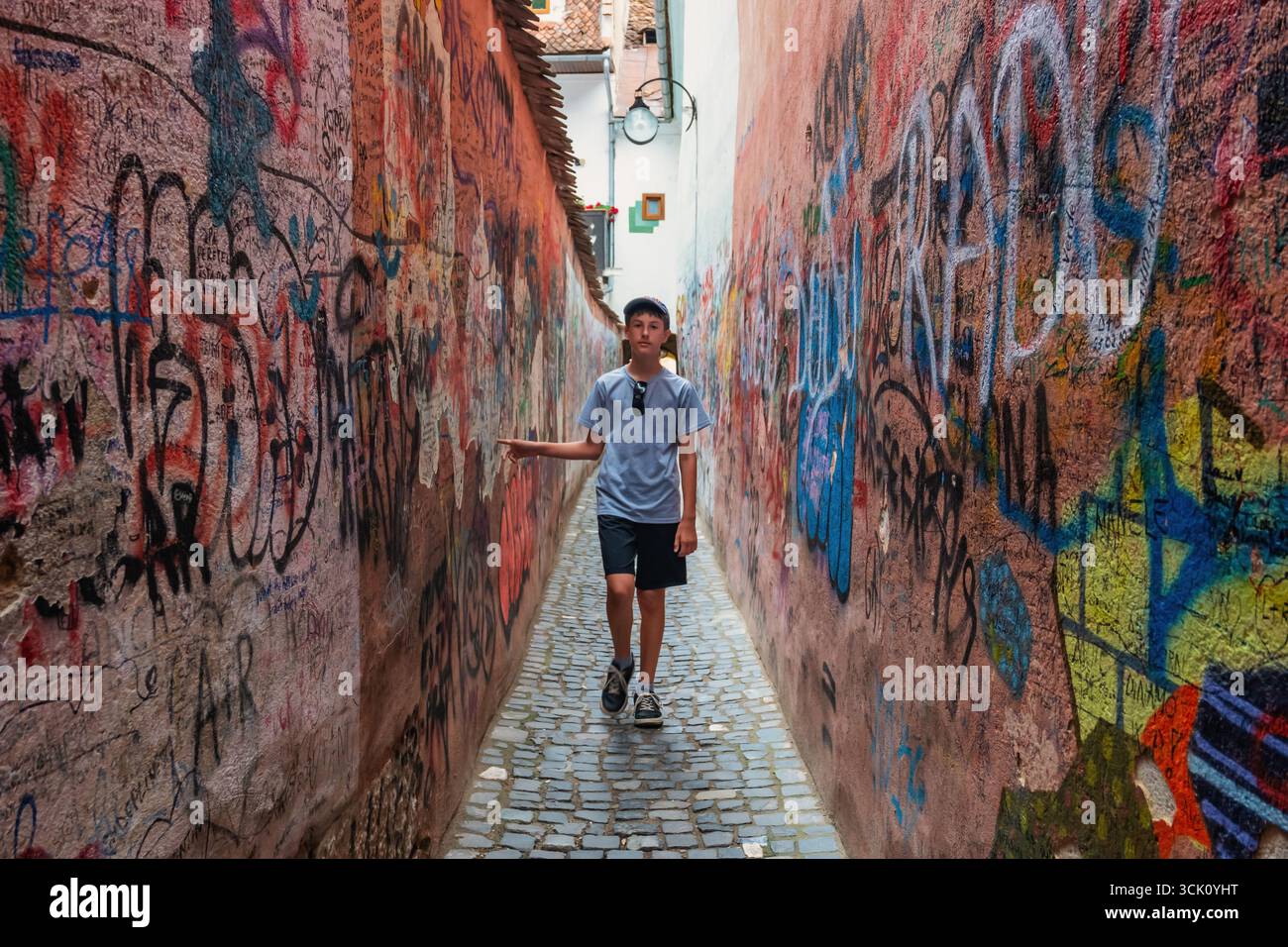 Adolescent marche dans une ruelle étroite dans la vieille ville de Brasov, Roumanie. Banque D'Images