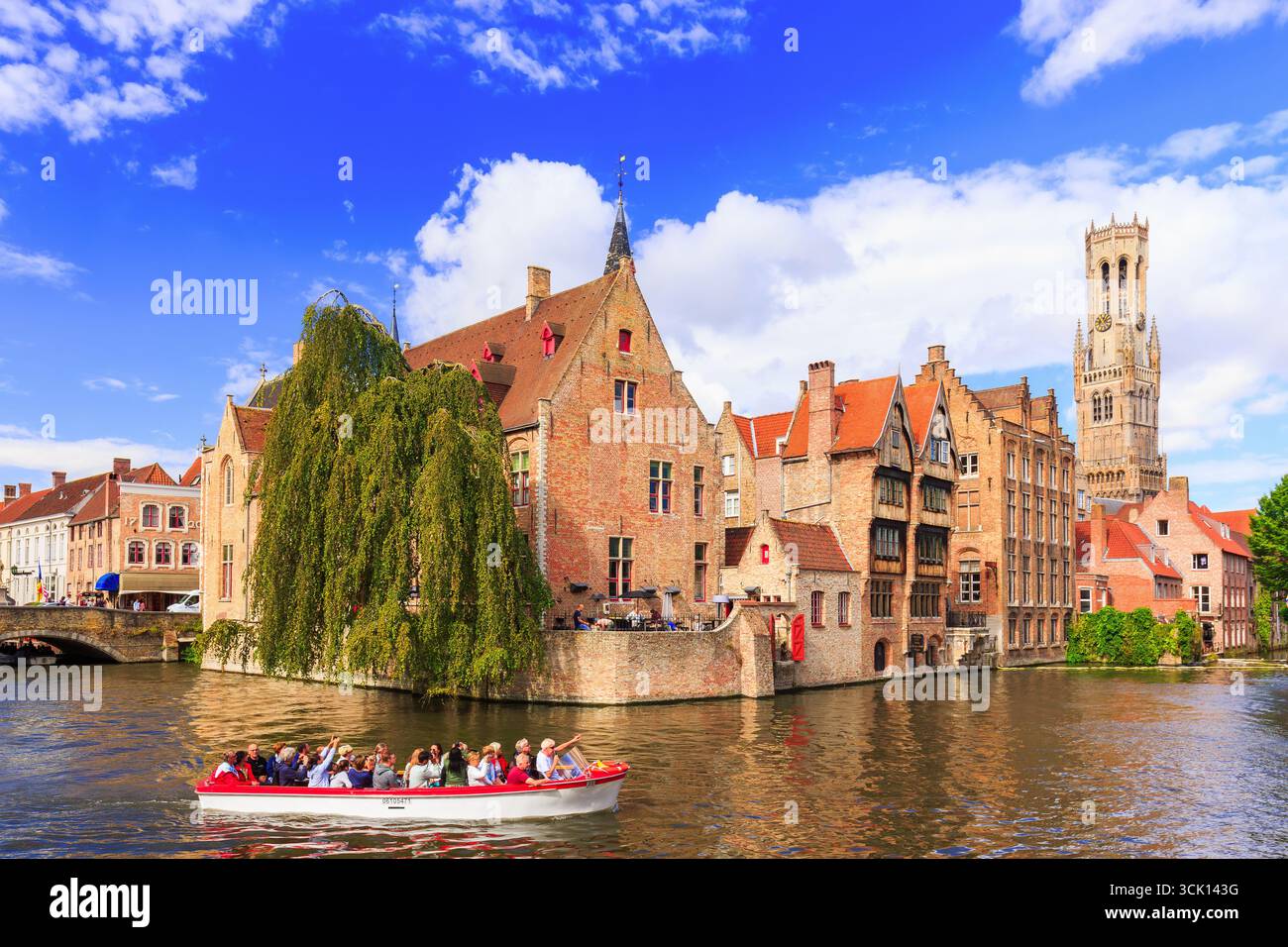 Bruges, Belgique - 10 août 2018 : le canal Rozenhoedkaai avec bateau touristique et le beffroi en arrière-plan. Banque D'Images