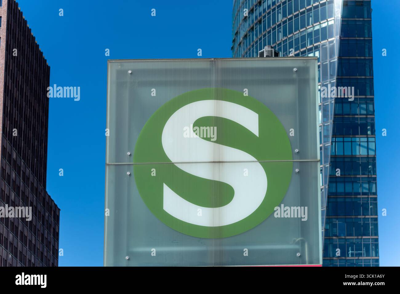 Un symbole S-Bahn vert s'allume devant les gratte-ciel modernes. Il indique l'entrée du système ferroviaire de la ville. Banque D'Images