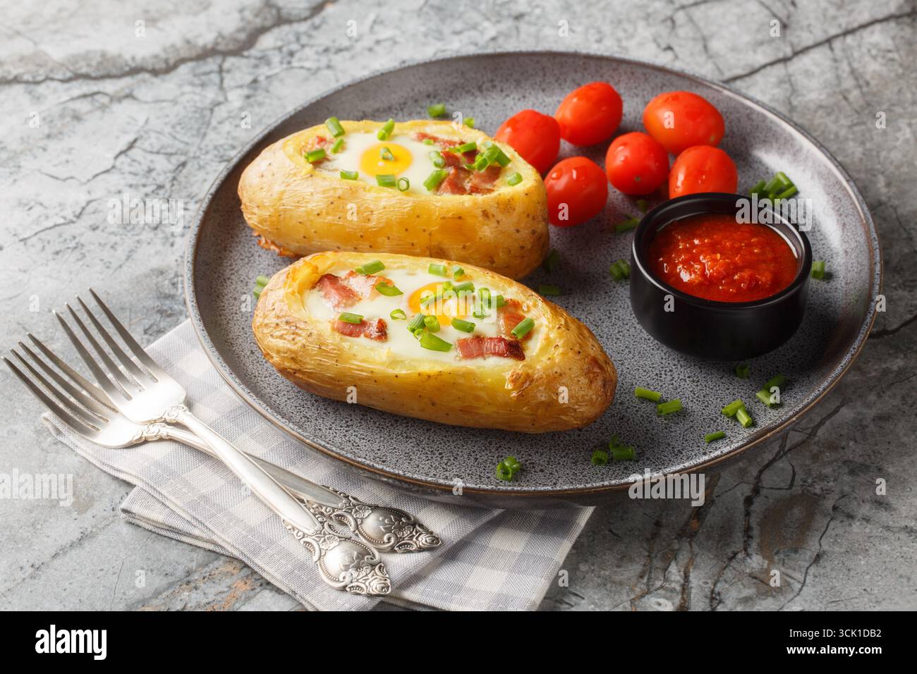 Pommes de terre farcies au bacon, aux légumes verts et aux œufs en gros plan sur l'assiette sur la table. Horizontal Banque D'Images