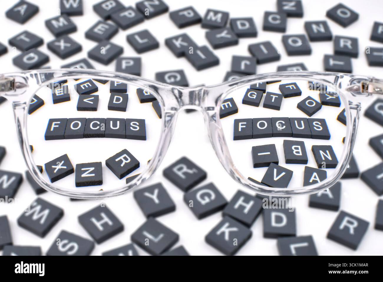 Smalls blocs de lettres de l'alphabet dans le focus vu à travers les stylos d'une paire de lunettes de lecture. Concept de vision et de vision. Banque D'Images