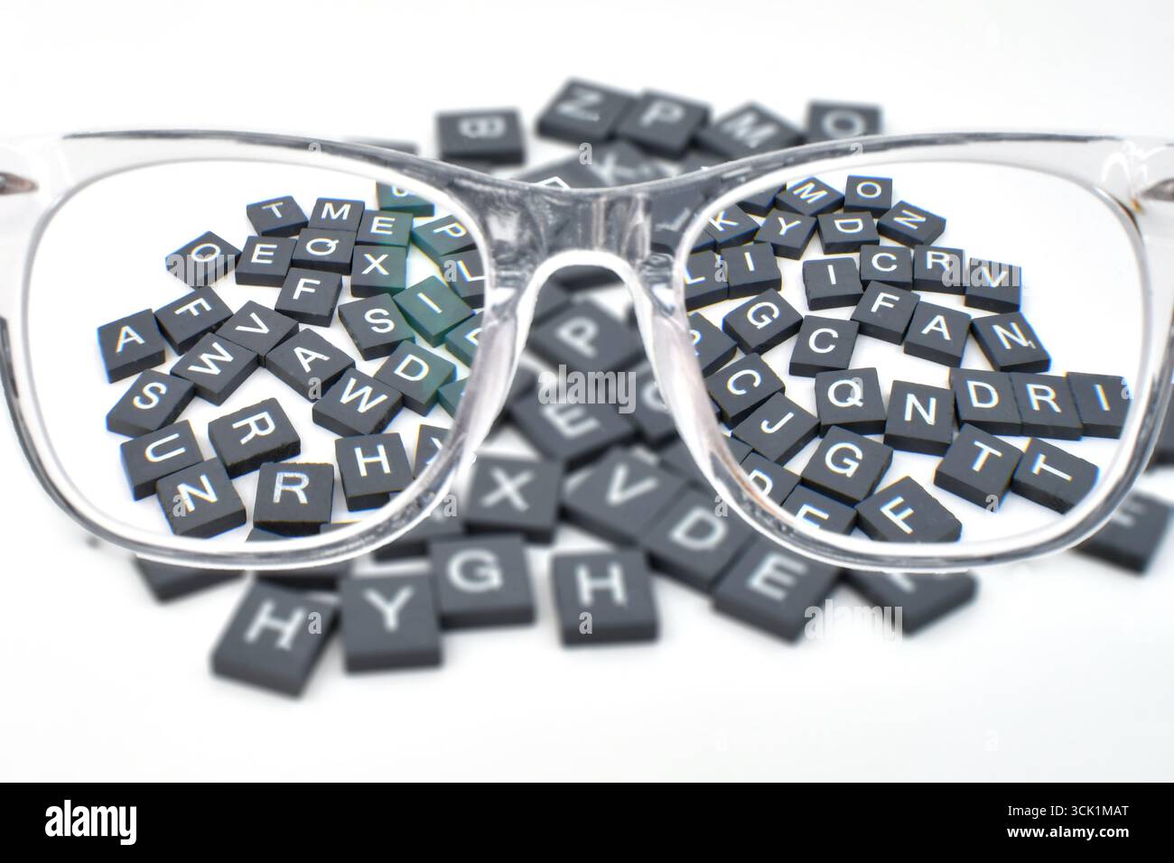 Smalls blocs de lettres de l'alphabet dans le focus vu à travers les stylos d'une paire de lunettes de lecture. Concept de vision et de vision. Banque D'Images