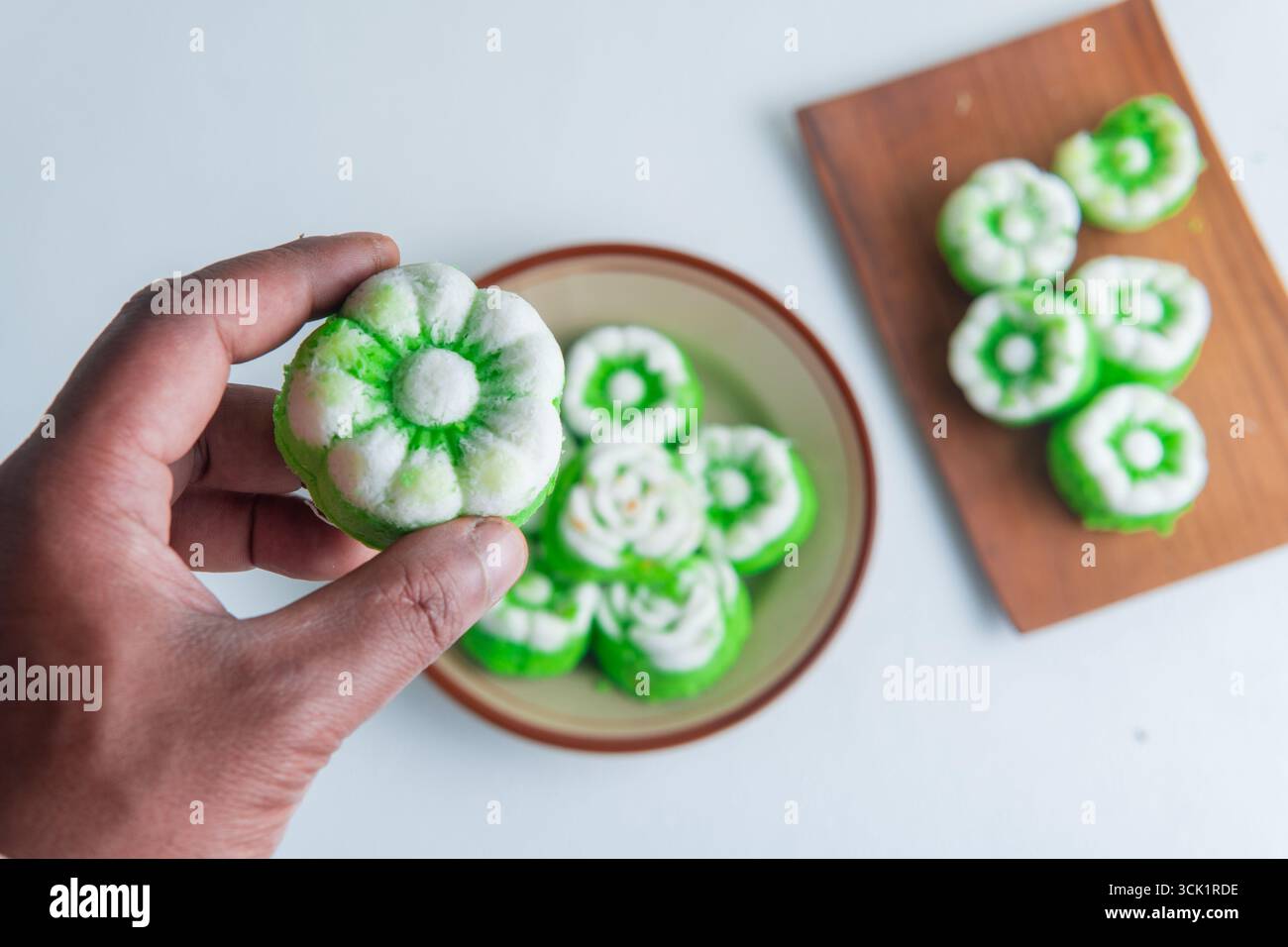 Main tenant un gâteau traditionnel indonésien cuit à la vapeur appelé putu ayu, saveur pandan avec garniture de noix de coco râpée, doux et sucré. Banque D'Images