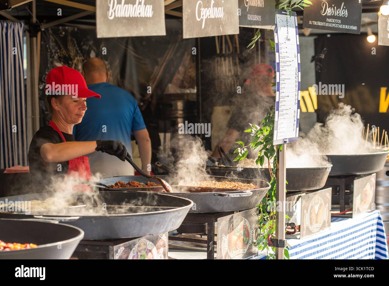 Un vendeur de nourriture de rue préparant des repas chauds dans de grandes casseroles à vapeur sur un marché de nourriture de rue et d'artisanat à Vilnius, Lituanie, Europe Banque D'Images