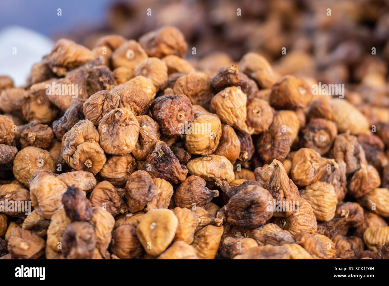 Une image en gros plan d'un grand tas de figues séchées, mettant en valeur leurs peaux texturées, froissées et leurs tons brun doré Banque D'Images