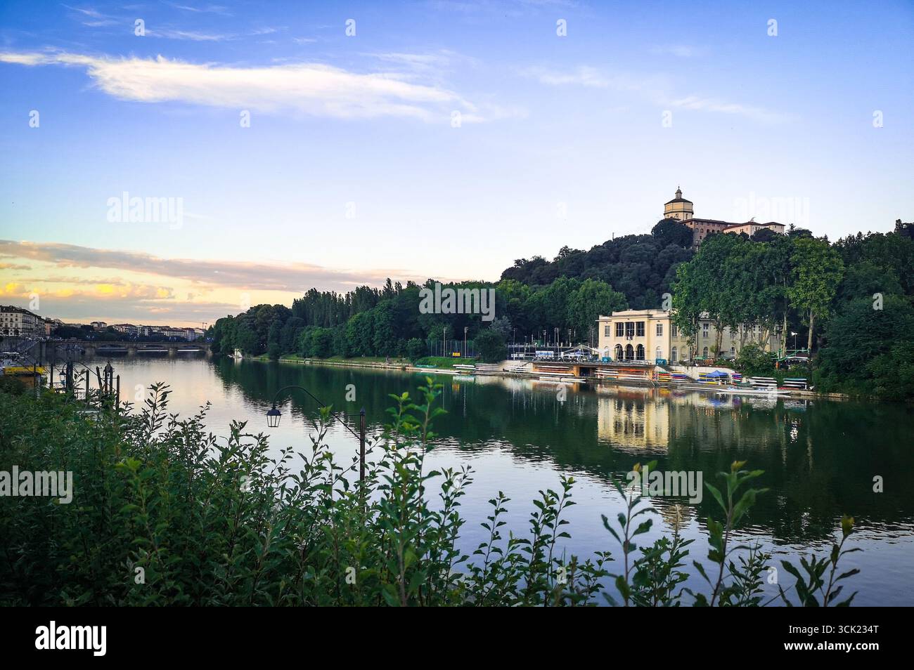 Une photo de paysage grand angle du fleuve po et de la ligne d'horizon de Turin au crépuscule. L'image présente l'eau réfléchissante avec un bâtiment de club d'aviron classique - Image de stock capturée avec un smartphone