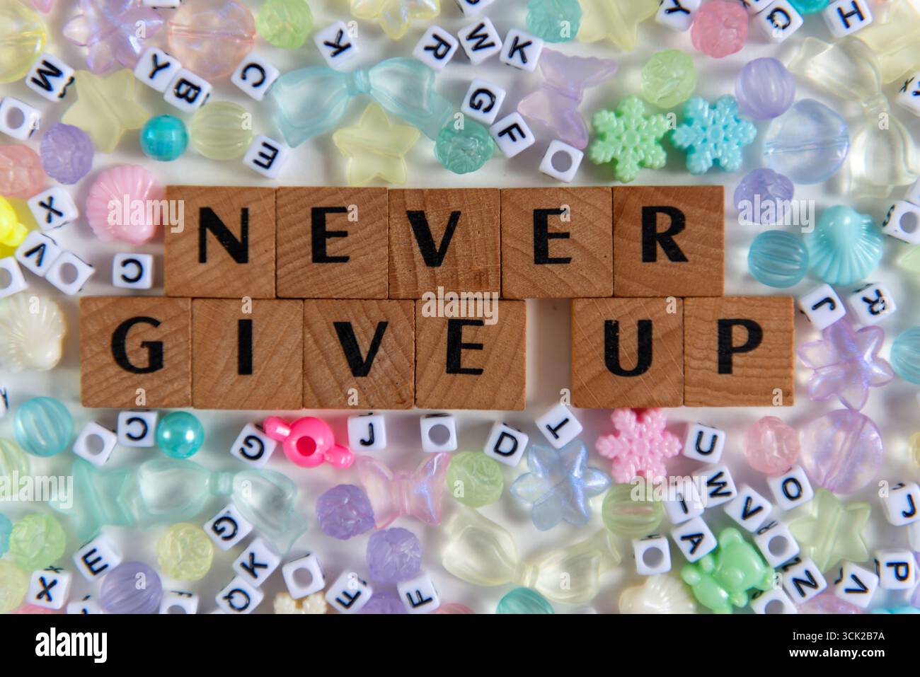 Citation inspirante « Never Late Up » orthographiée avec des carreaux de bois, entourée de perles pastel et de lettres en plastique. Position plate créative et motivante Banque D'Images