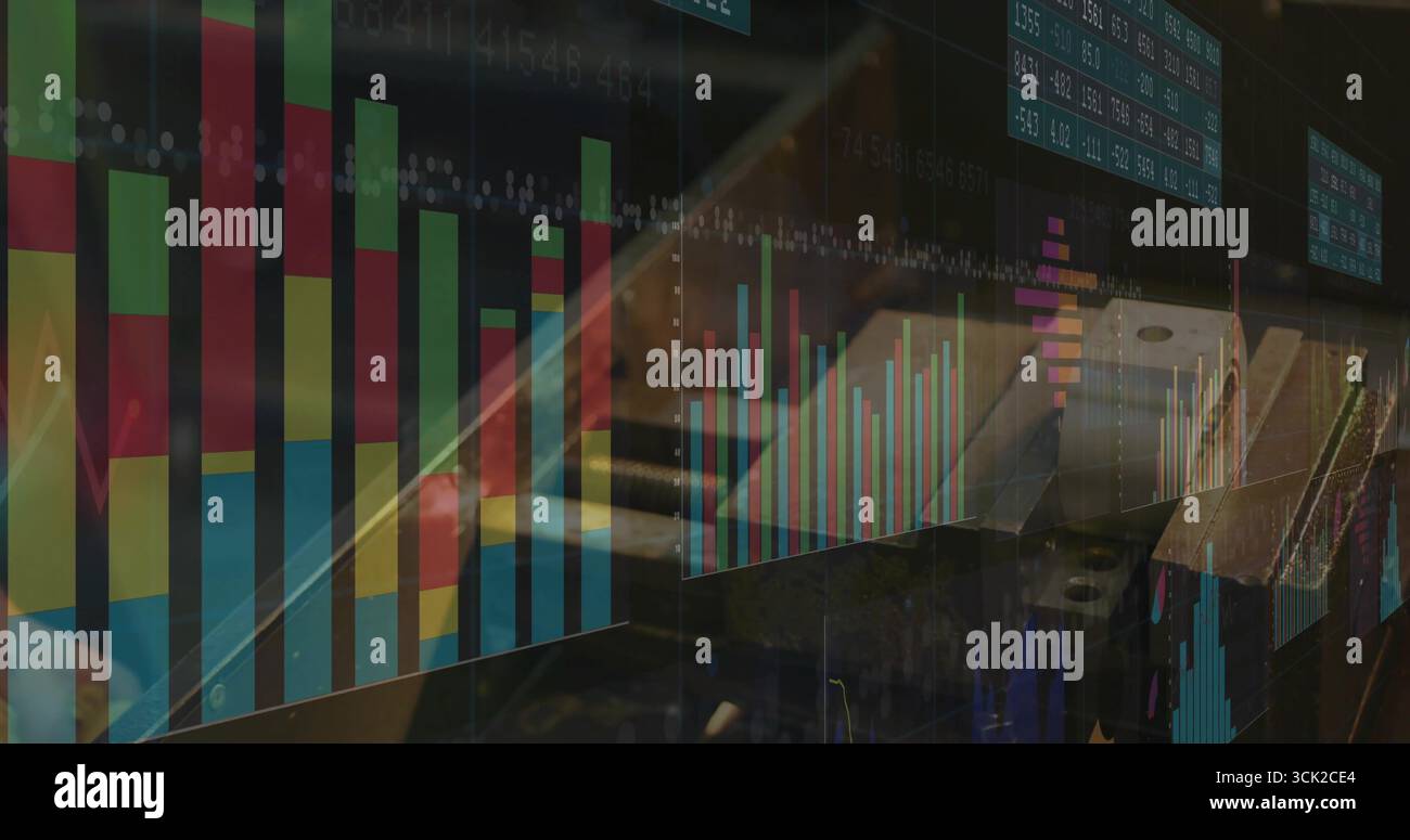 Homme adulte portant la chemise boutonnée tapant sur le clavier d'ordinateur portable dans le bureau, avec des graphiques financiers Banque D'Images