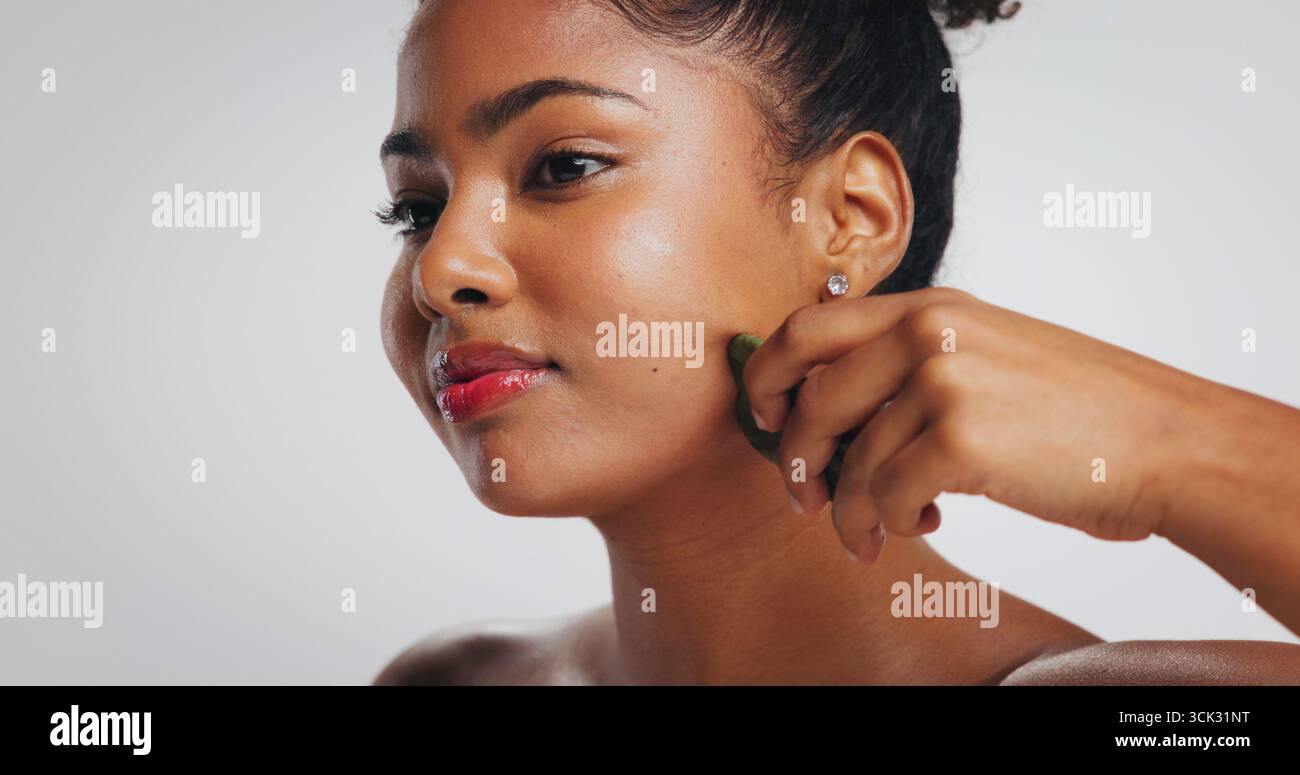 Gua Sha, soin de la peau et femme africaine en studio pour la désintoxication, le drainage lymphatique et le toilettage. Spa, espace et personne avec des outils de beauté pour le massage facial Banque D'Images