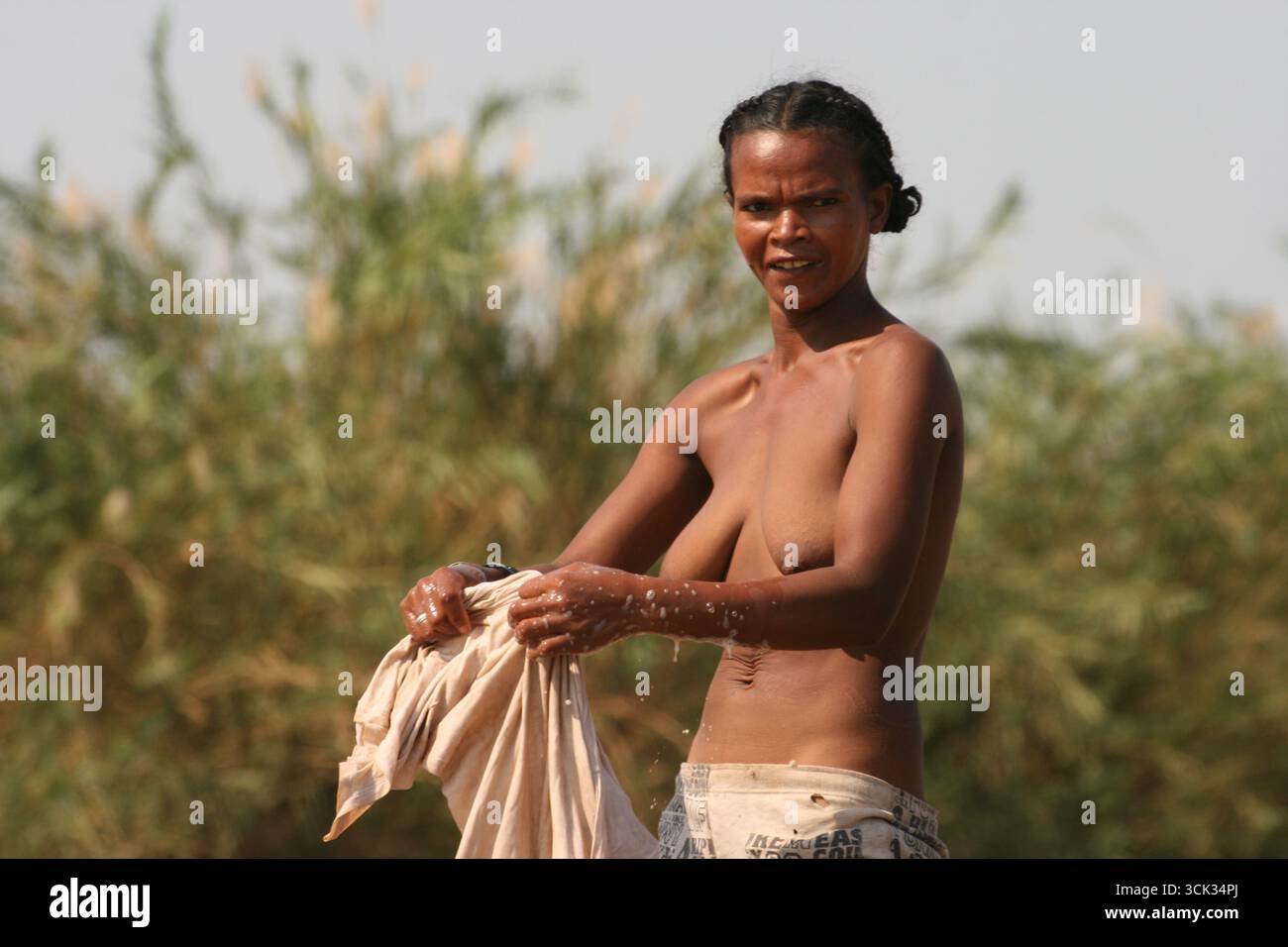 Femme malgache faisant la lessive à la rive à Madagascar, Afrique. Lavage traditionnel et vie quotidienne rurale. Banque D'Images