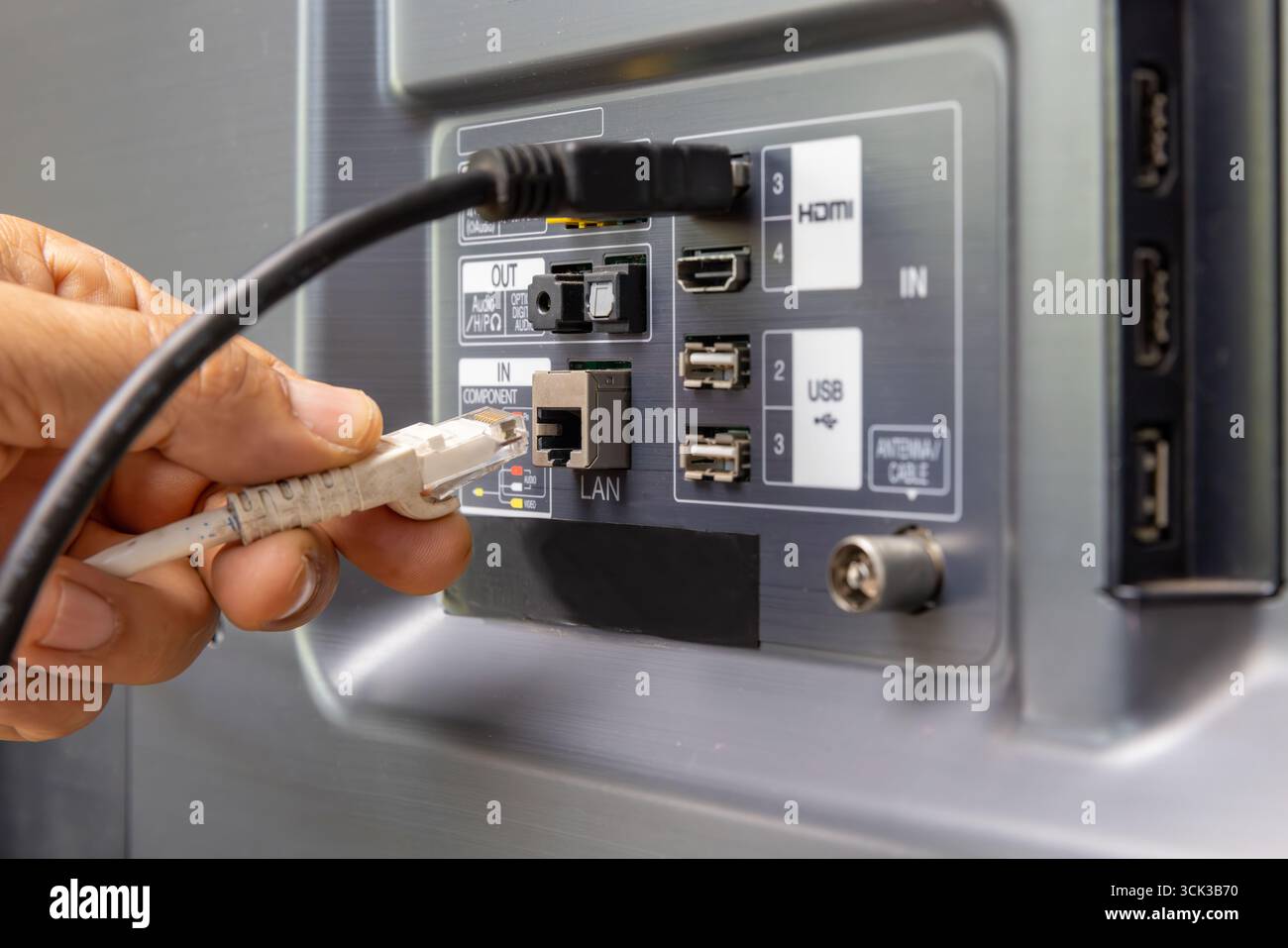 Man connecte le câble Internet au téléviseur. Banque D'Images