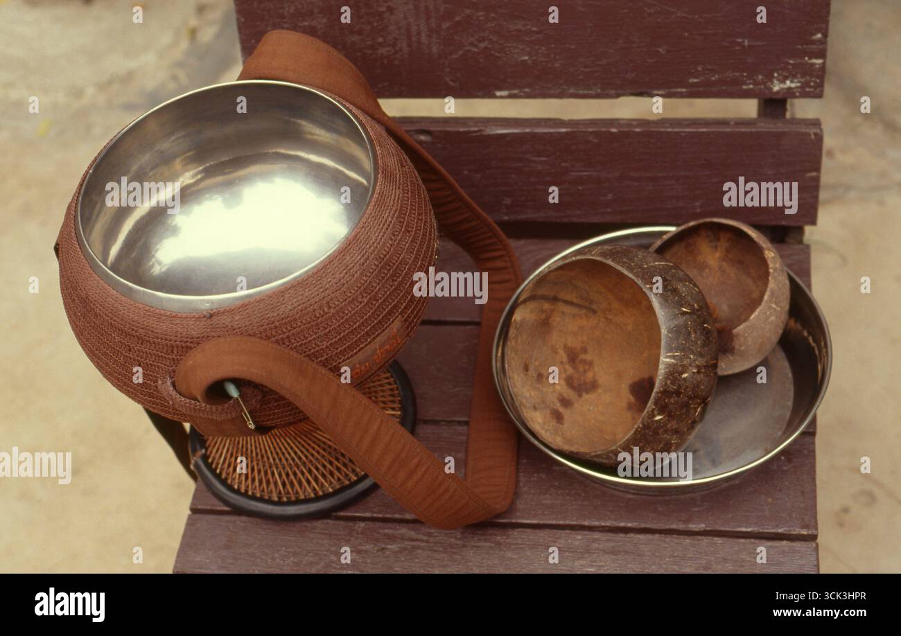 Thaïlande : saladier de moine bouddhiste typique avec des récipients pour boire et manger de la noix de coco. Dans le bouddhisme Theravada, les moines (Pāli : bhikkhus) et les religieuses font un almsround quotidien (ou pindacara) pour recueillir de la nourriture. Cela est souvent perçu comme donnant aux laïcs la possibilité de faire du mérite (Pāli : puñña). L'argent ne devrait pas être accepté par un moine bouddhiste ou une religieuse au lieu ou en plus de la nourriture, bien que de nos jours peu de moines et de religieuses respectent cette règle (l'exception étant les moines et les religieuses de la tradition de la forêt thaïlandaise et d'autres traditions Theravada qui se concentrent sur le vinaya et la pratique de la méditation). Banque D'Images