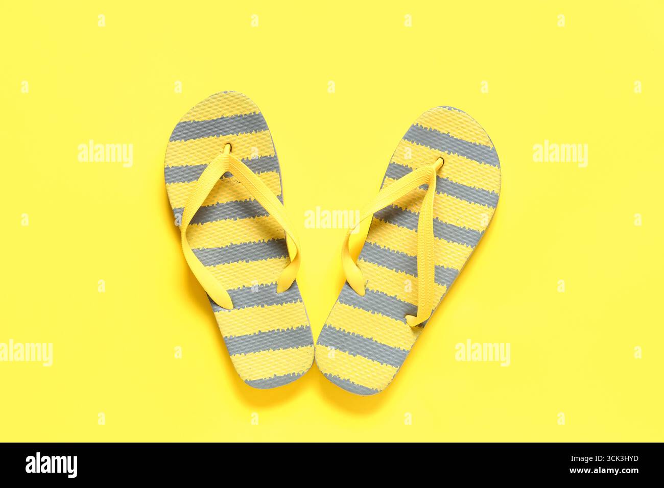 Tongs rayées élégantes sur fond jaune Banque D'Images