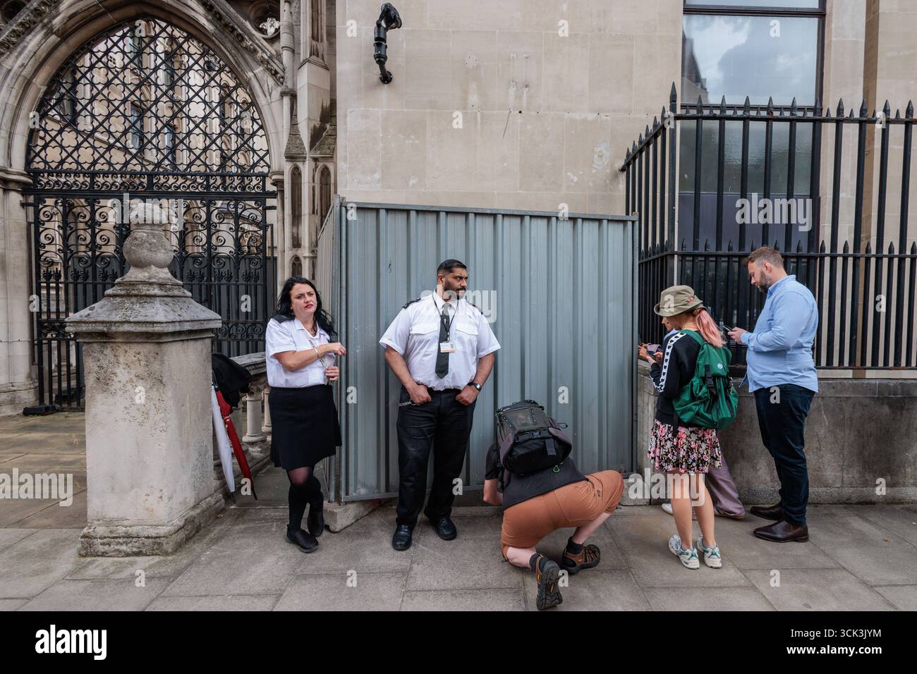 Londres, Royaume-Uni. 9 septembre 2025. Les gens font la queue aux côtés des gardes de sécurité pour voir une nouvelle œuvre d'art Banksy sur un mur extérieur du Queen's Building des cours royales de justice. HM courts and Tribunals a indiqué que l'œuvre d'art, qui montre un juge dans une perruque et une robe utilisant un marteau pour frapper un manifestant avec une pancarte de sang éclaboussée, sera retirée. Crédit : Mark Kerrison/Alamy Live News Banque D'Images