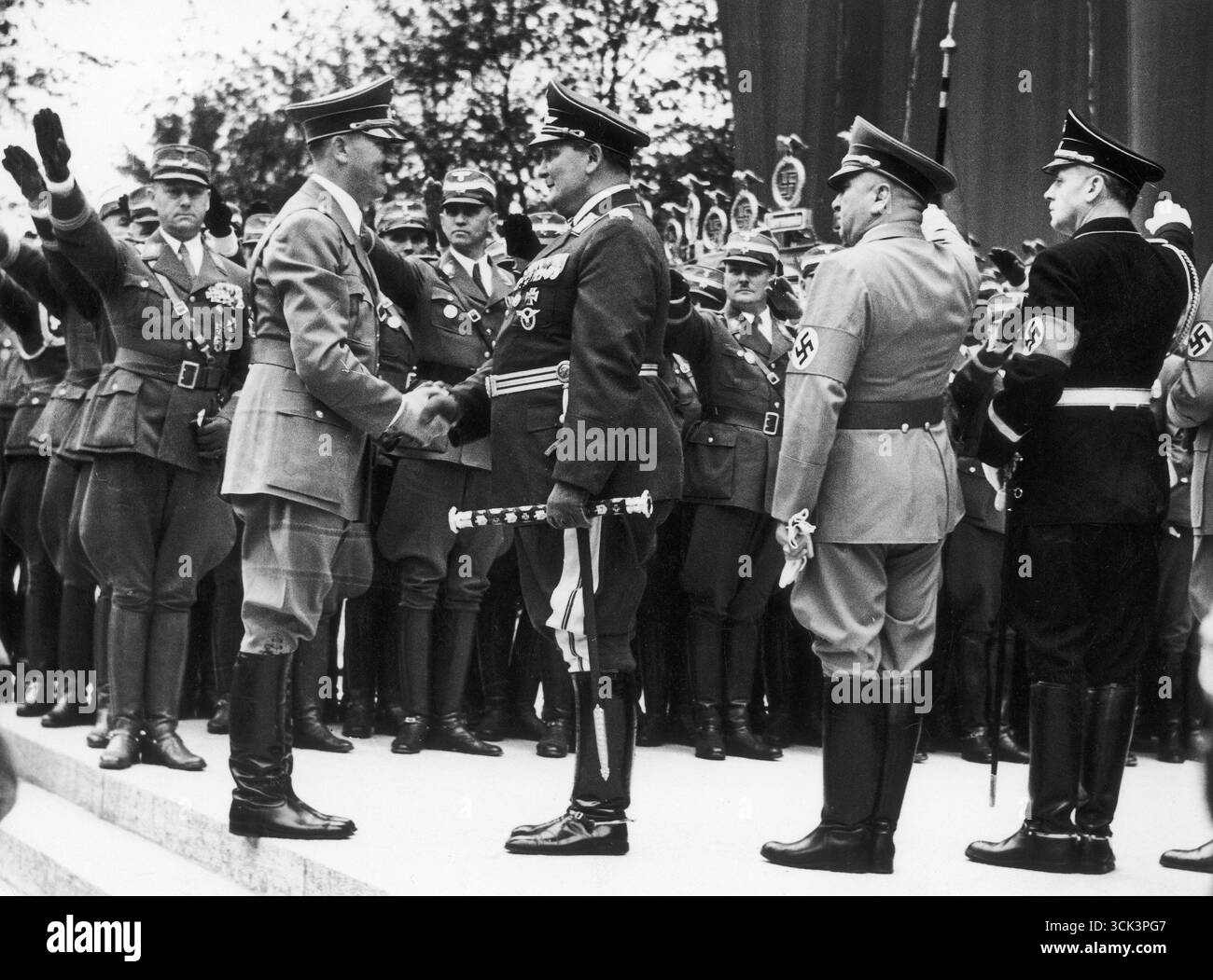 Rencontre nazie – Adolf Hitler serrant la main à Hermann Goring. Les nazis saluent en arrière-plan. 1938 Banque D'Images