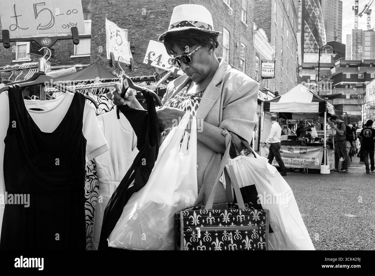 Femme regardant des robes à Market Stall, Petticoat Lane, Londres, Royaume-Uni Banque D'Images