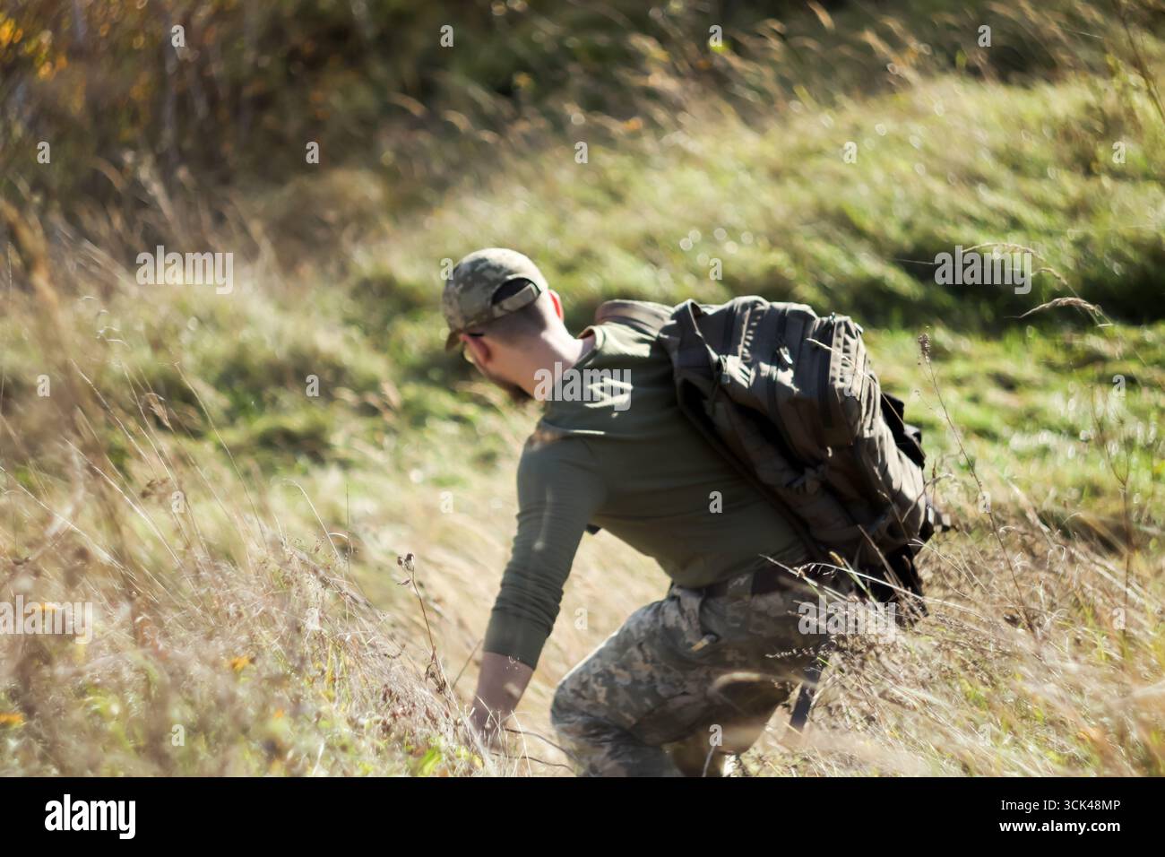 Un soldat de l'OTAN de l'Ukraine ou des États-Unis de l'arrière dans l'herbe des montagnes. Montagne d'entraînement physique soldat de l'OTAN. la coopération militaire descend Banque D'Images