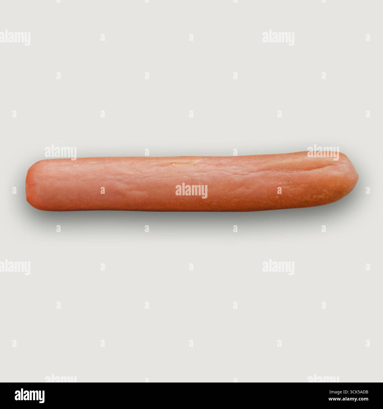 Une saucisse de hot dog unique sur un fond Uni, généralement utilisée dans divers plats culinaires ou servie comme collation. Banque D'Images