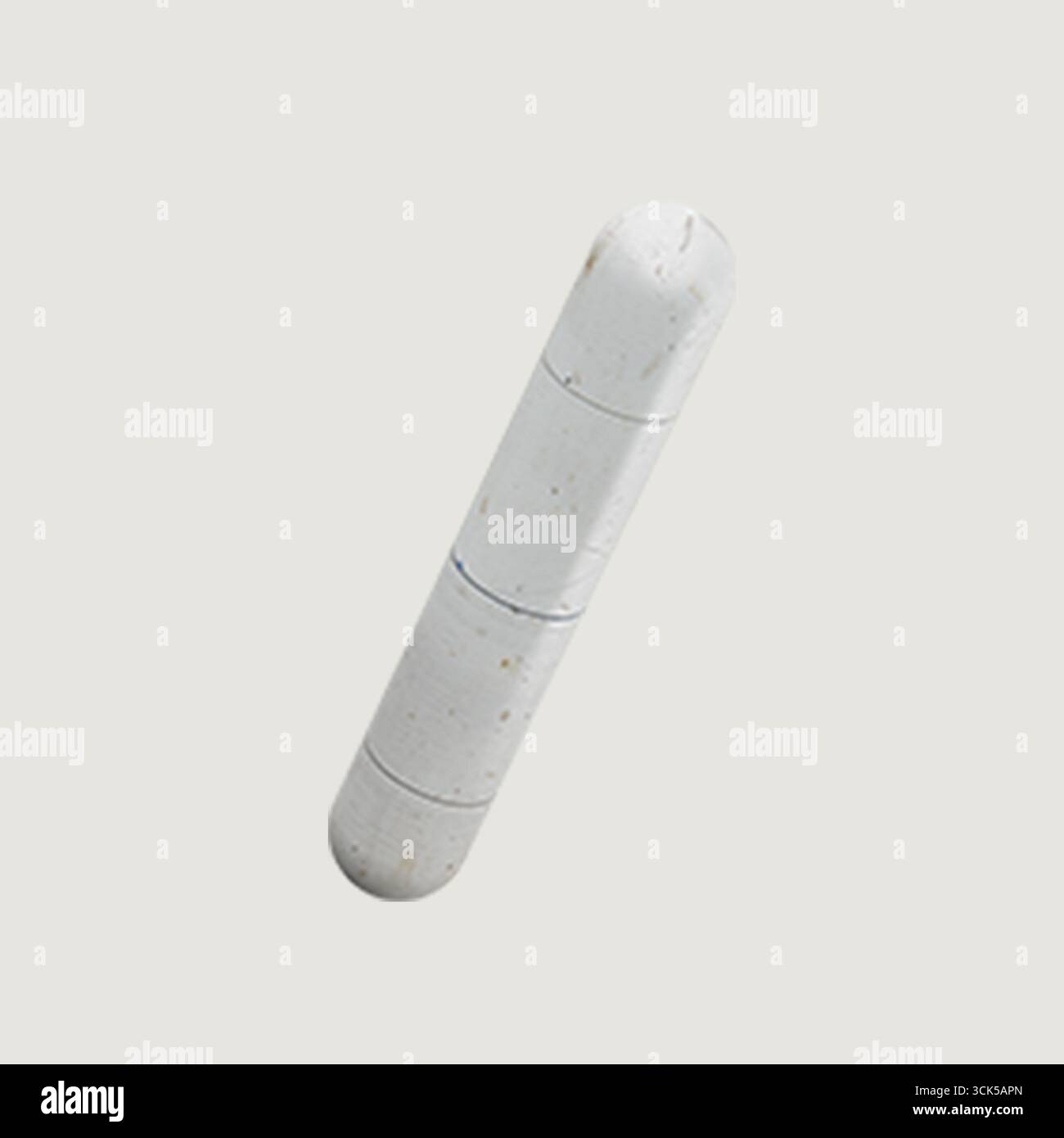 Un objet cylindrique blanc avec trois lignes horizontales, peut-être une capsule ou une pilule. Banque D'Images