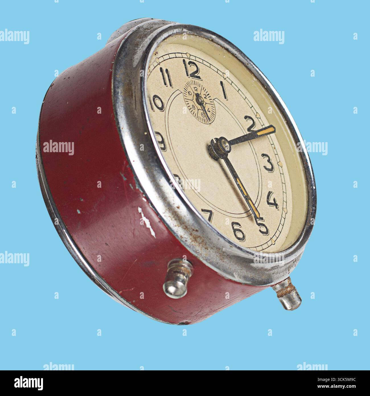 Un réveil rouge vintage au design classique, avec un visage rond et des aiguilles des heures et des minutes traditionnelles. Banque D'Images
