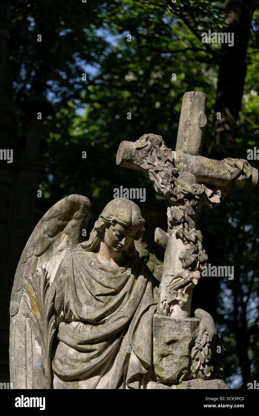 Statue d'un ange avec croix, sculpture en pierre tombale ancienne dans le cimetière orthodoxe dans le quartier de Wola de Varsovie en Pologne. Banque D'Images