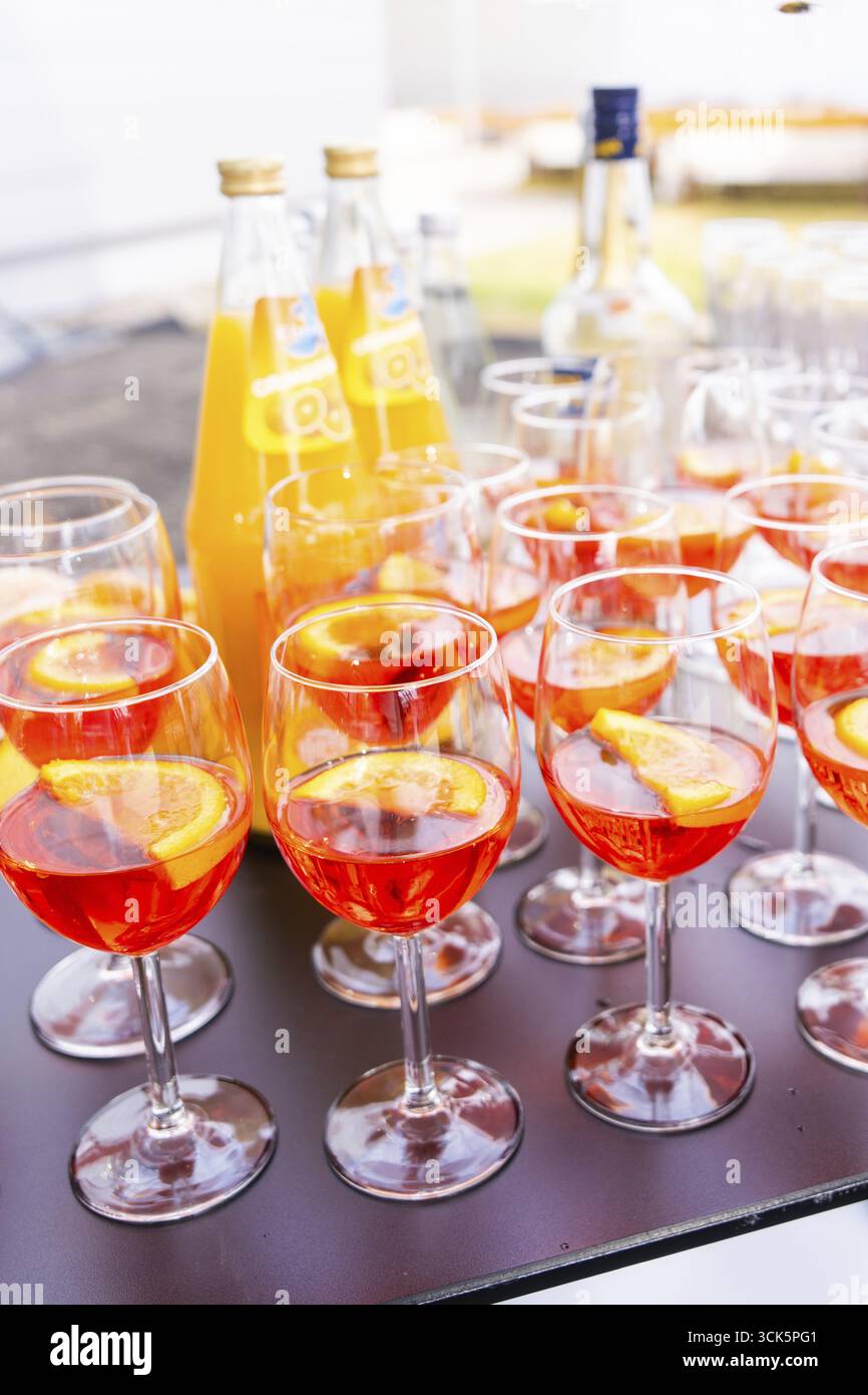 Plusieurs verres à cocktail avec une boisson de couleur orange et des tranches d'orange, disposés sur une table à l'extérieur, lac de Constance, Allemagne Banque D'Images