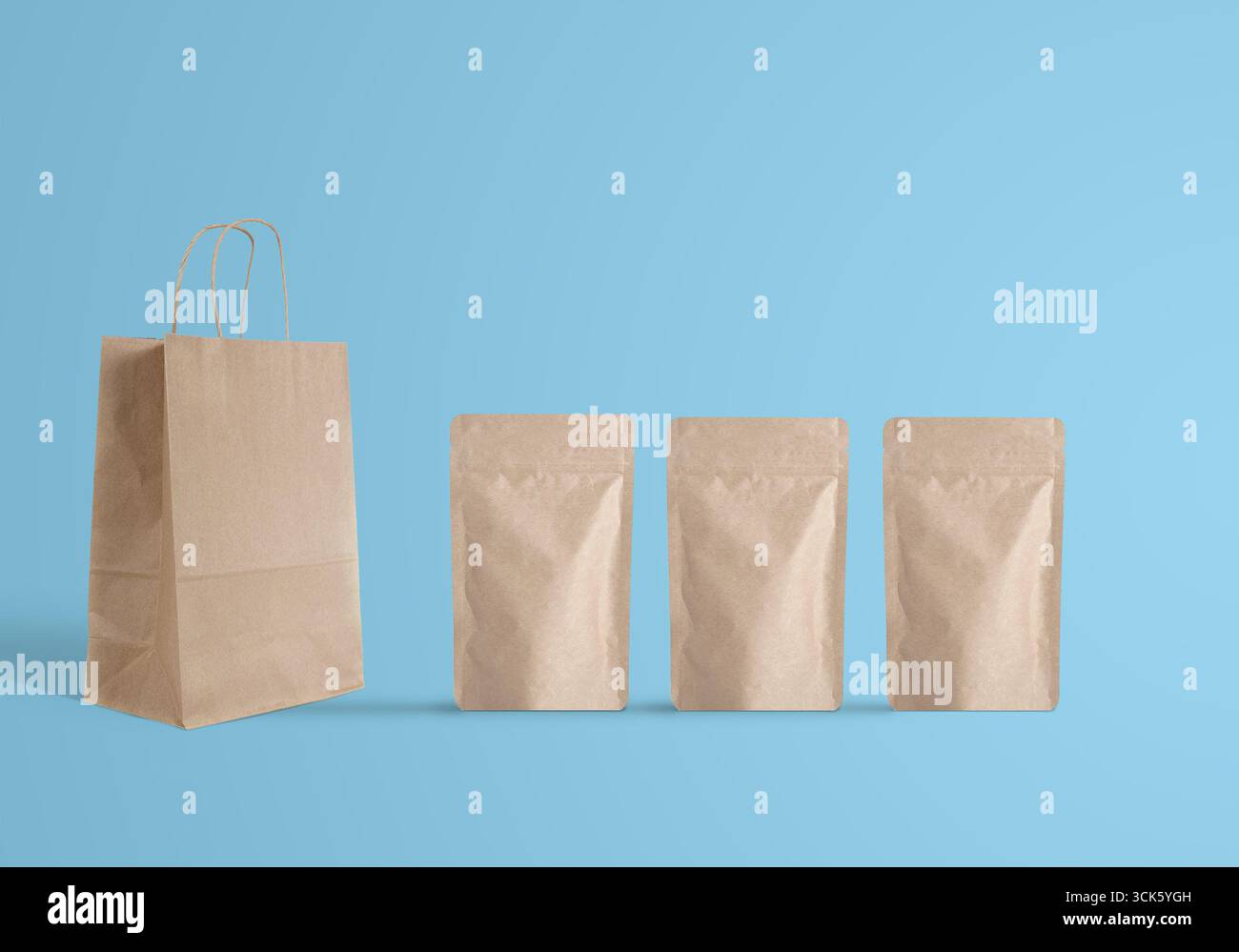 Un simple affichage d'un sac à provisions en papier à côté de trois pochettes en papier kraft identiques, présentant la conception de l'emballage. Banque D'Images