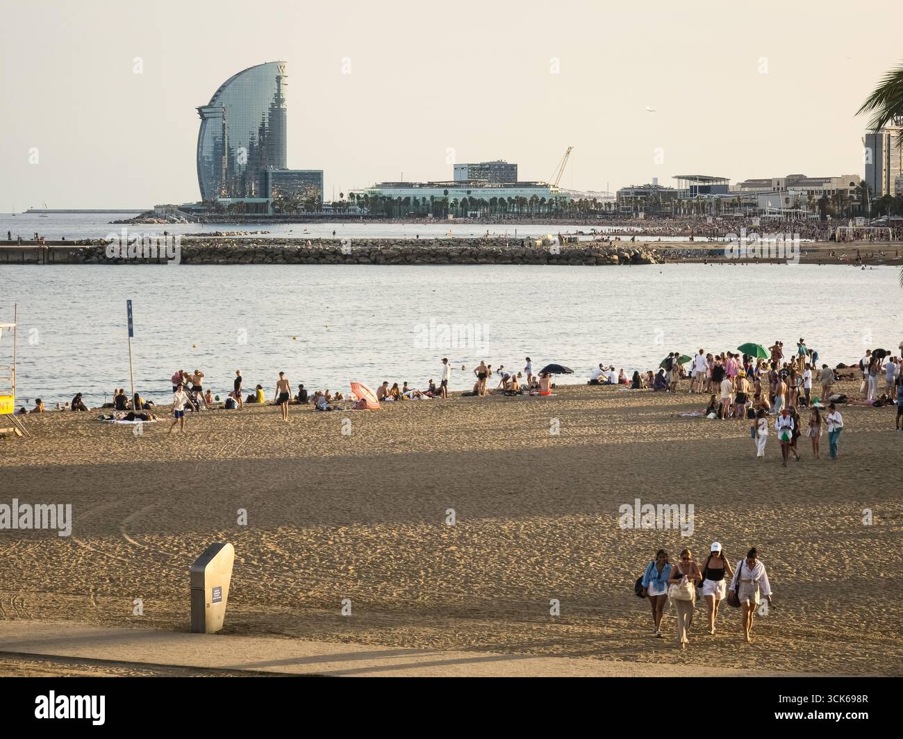 Barcelone, Espagne. 06 septembre 2025, touristes appréciant la plage de Barceloneta avec W Barcelona Hotel en arrière-plan Banque D'Images