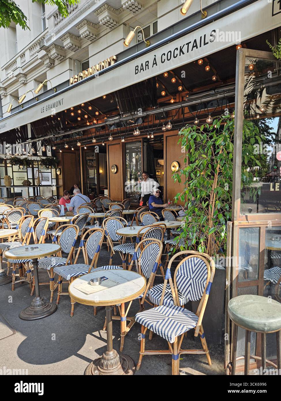Paris, France. 14 mai 2025, café parisien en plein air au soleil avec les clients qui profitent de leur temps Banque D'Images